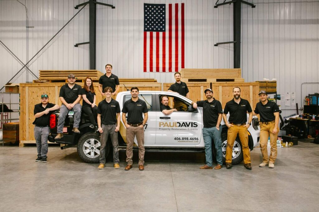 Paul Davis Restoration of Southwest Montana team standing with service truck inside warehouse, professional property damage restoration experts ready for emergency response