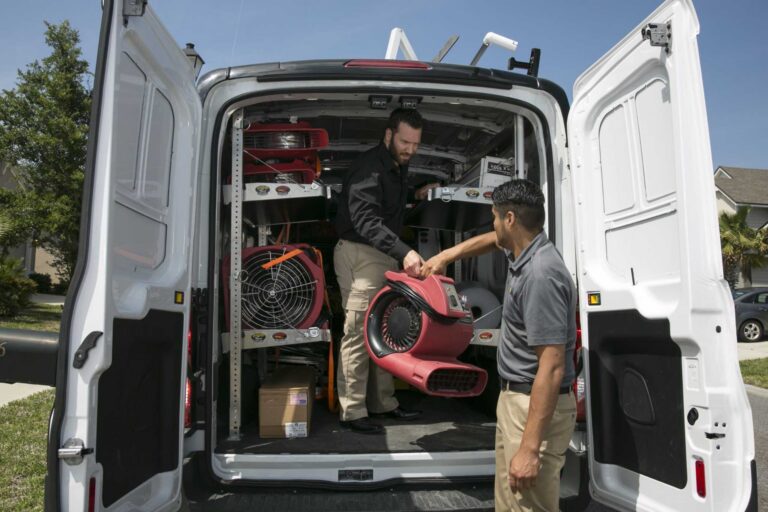 Paul Davis Restoration technicians unloading commercial storm damage restoration equipment and industrial drying fans from emergency response van for property recovery services
